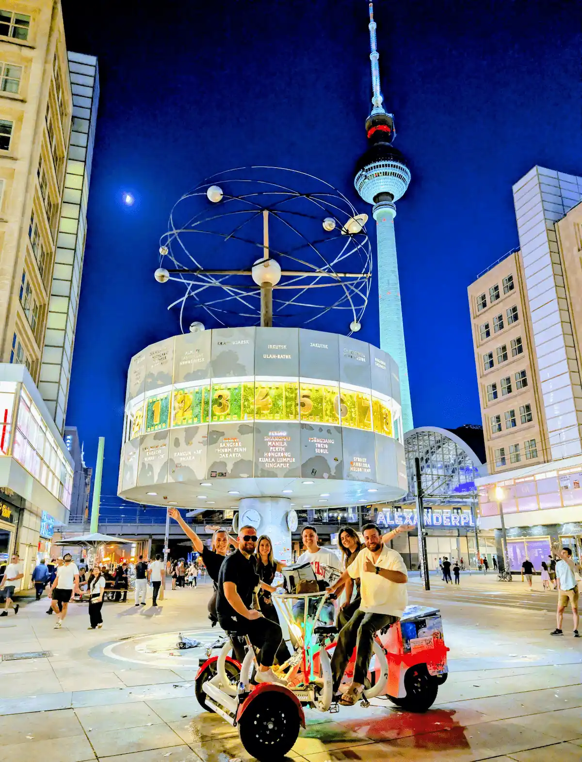 Die bessere, wendige und kultivierte Alternative zum Bierbike: Conference Bike am Alexanderplatz vor dem Hintergrund von Fernsehturm und Weltzeituhr auf einer Sightseeing Tour – Lights of Berlin.